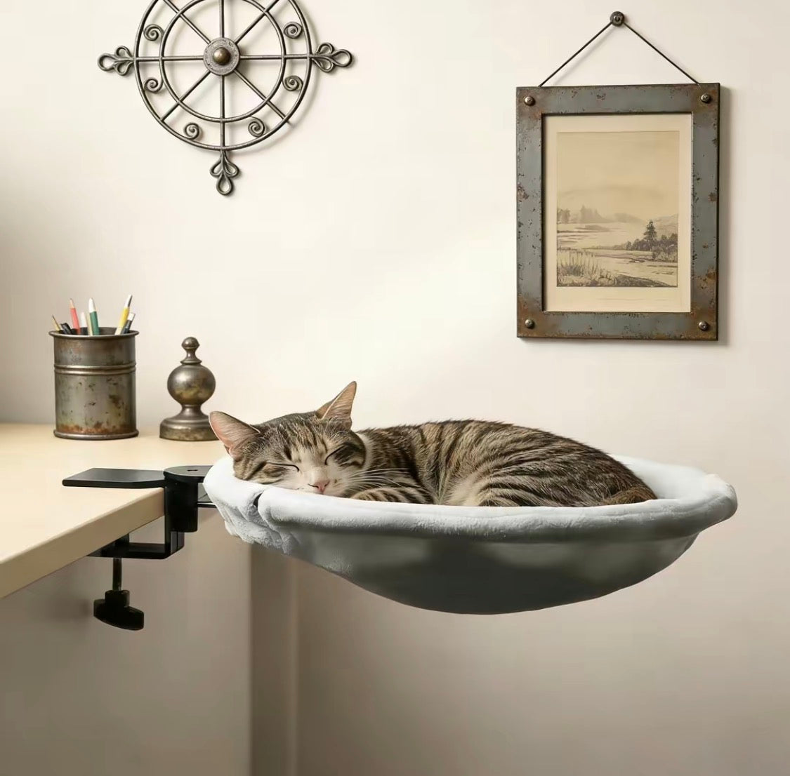 Tabby cat napping in the Adjustable Cat Desk Bed clamped to a home office desk